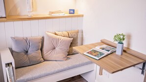 A modern living room with a sofa, a small table, a plant, and a wall-mounted speaker. - Astonishing Home Office Balcony Cebu CBD Furnished (Cebu City)
