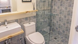 A modern bathroom with a glass-enclosed shower, a white toilet, a sink, and a mirror above the sink. - Astonishing Home Office Balcony Cebu CBD Furnished (Cebu City)