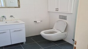 Une salle de bain avec un lavabo blanc, des toilettes et un miroir doté d’un cadre doré.