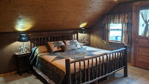 Una camera da letto con pannelli in legno, un letto, due comodini, una finestra con tende e una porta.