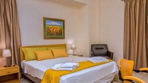 Une chambre d’hôtel avec un lit, une chaise, une table de chevet, une lampe et un tableau au mur.