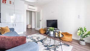 Una sala de estar moderna con un sofá, una mesa de centro con una planta, un televisor y otra planta en maceta.