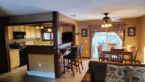 A modern kitchen with wooden cabinets, a central island, and pendant lighting.