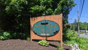 A wooden sign with the text "Adirondack Diamond Point Lodge" surrounded by mulch and rocks.