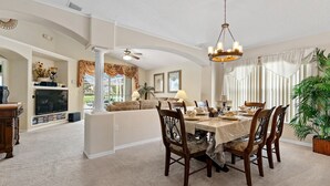 A dining area with a table set for four, surrounded by wooden chairs. - 4BR/3Bath Home, pool/spa, game room, lake view. Closer to ALL ATTRACTIONS (Kissimmee)