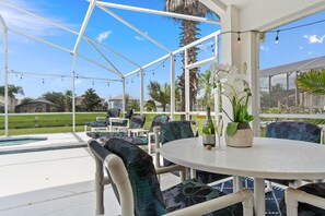 An outdoor patio with a round table and chairs, surrounded by a white pergola structure.
