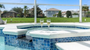 A hot tub with two glasses of champagne, surrounded by a white fence and a clear blue sky. - 4BR/3Bath Home, pool/spa, game room, lake view. Closer to ALL ATTRACTIONS (Kissimmee)