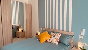 A modern bedroom with a large bed, a nightstand, a bedside table, and a wardrobe. - Two-storey apartment for 4 people [Casa Antonietta] (San Paolo Bel Sito)