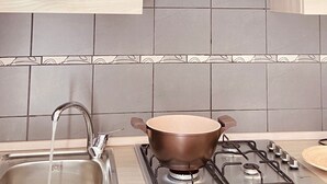 A modern kitchen with a stainless steel range hood, a gas stove, and a sink with running water. - Two-storey apartment for 4 people [Casa Antonietta] (San Paolo Bel Sito)