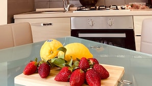 A modern kitchen with a glass table displaying fresh strawberries and a lemon. - Two-storey apartment for 4 people [Casa Antonietta] (San Paolo Bel Sito)