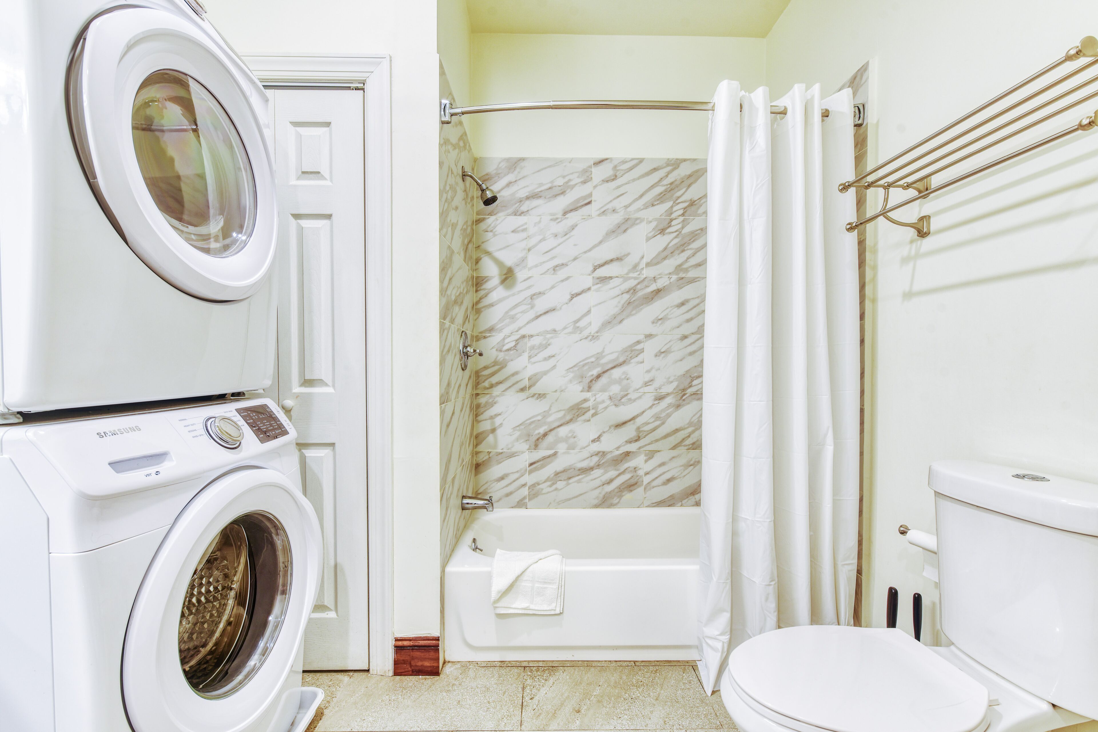 Un baño pequeño con lavadora, bañera y retrete.