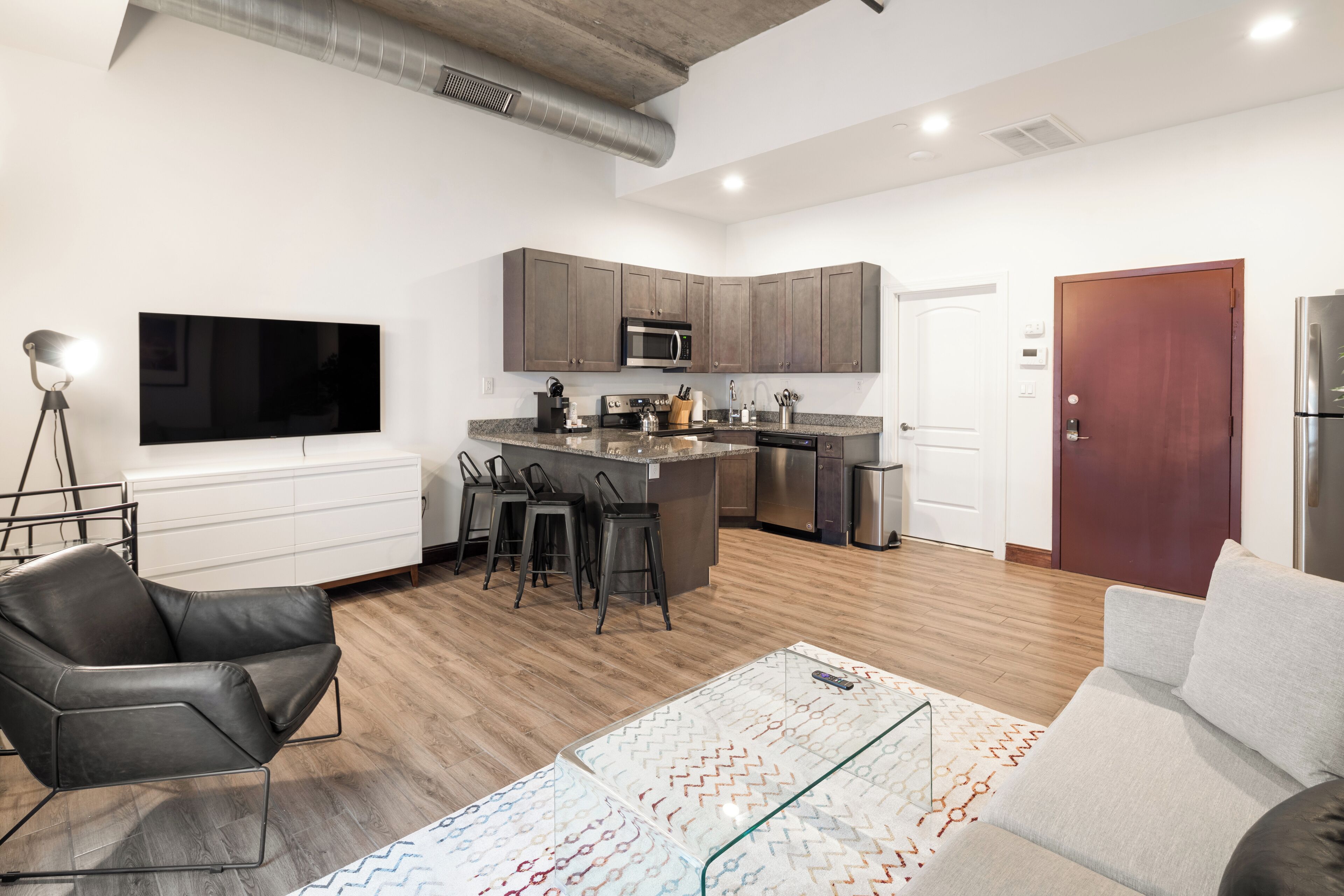 Una cocina moderna con una isla central, taburetes de bar y un televisor de pantalla plana.