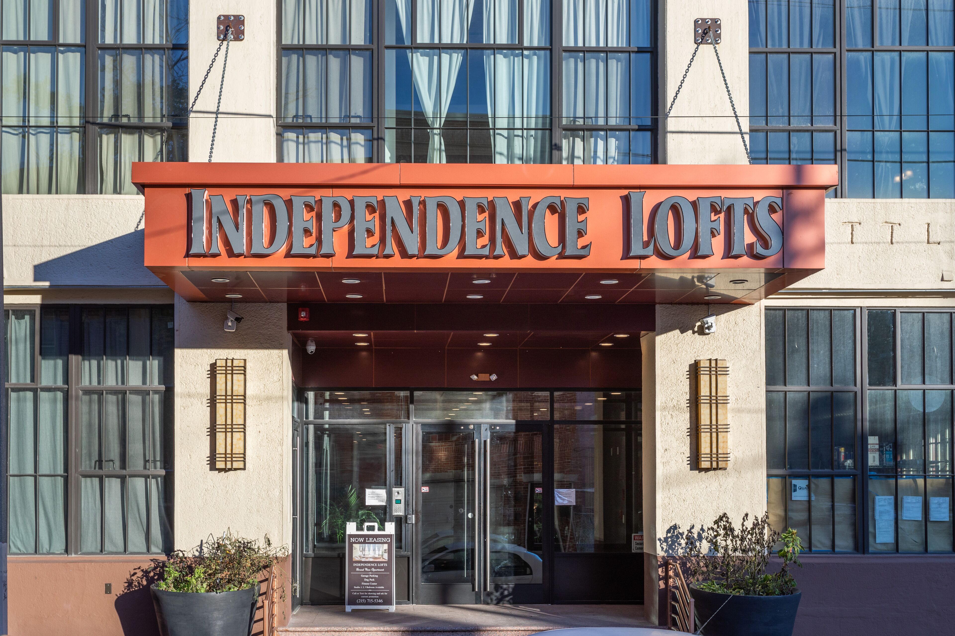 Independence Lofts with a modern entrance, large glass doors, and a prominent orange sign.