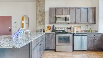 A modern kitchen with granite countertops, stainless steel appliances, and grey cabinetry.