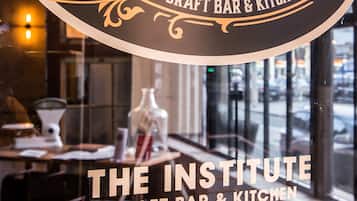 A sign for The Institute Craft Bar & Kitchen with open hours from 11 AM to 2 AM, Monday to Sunday.