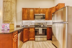 A kitchen with wooden cabinets, stainless steel appliances, and a granite countertop. -  Sosuite at Independence Lofts - Callowhill (Philadelphia)