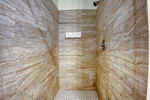 A shower with marble walls and a tiled floor.