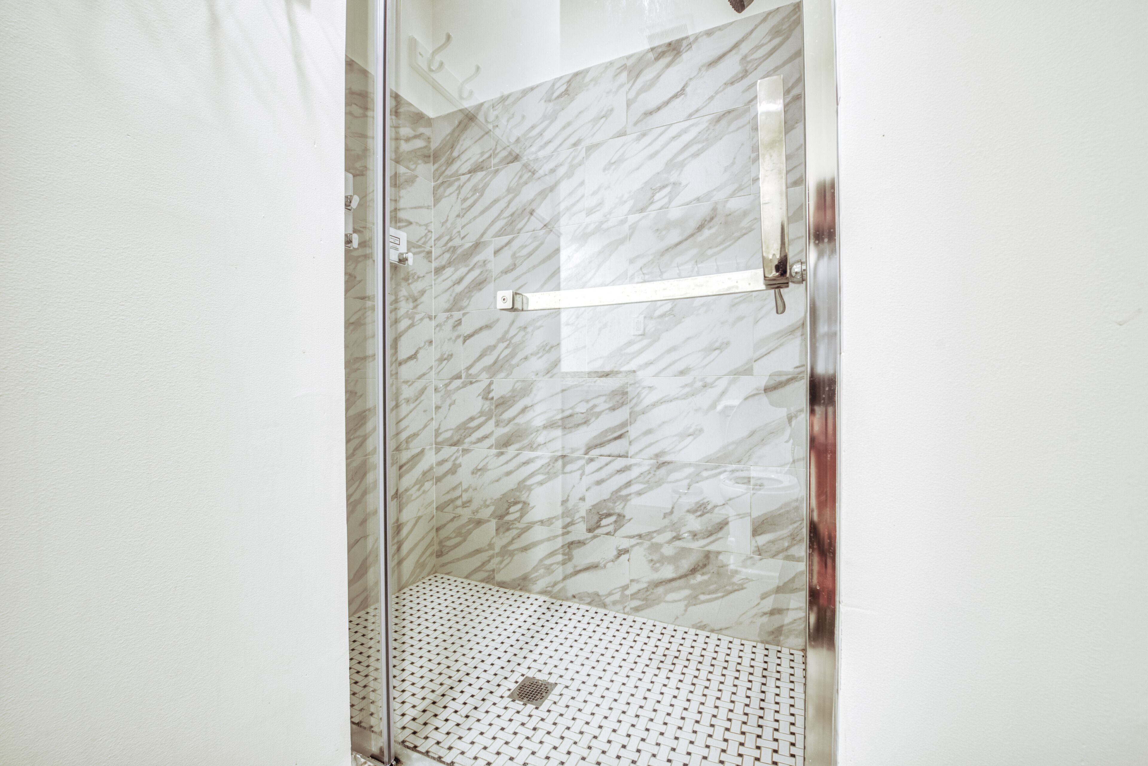 A shower with a glass door and a metal handle.
