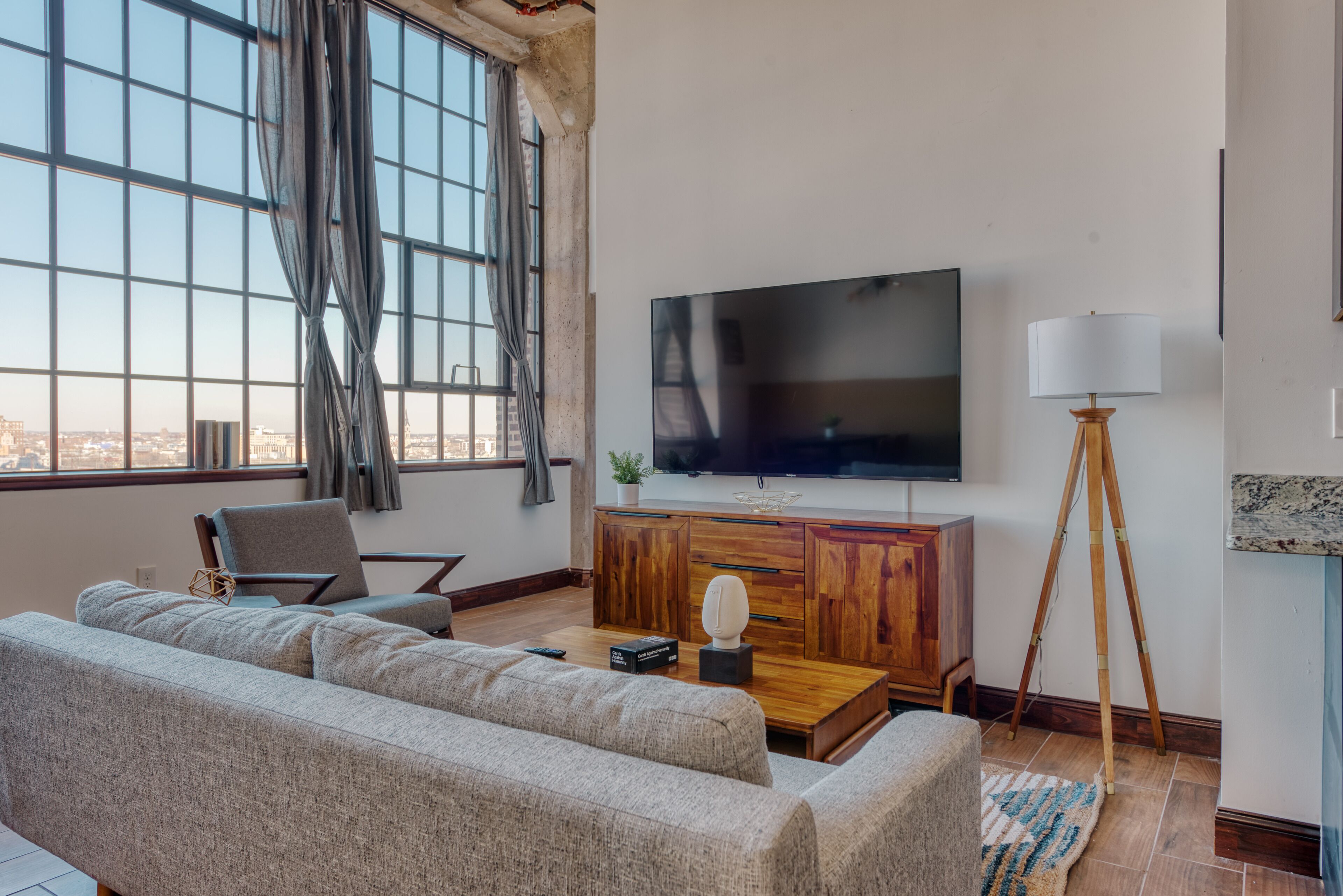 Un salon moderne avec une grande télévision, un canapé, une table basse en bois et un lampadaire.
