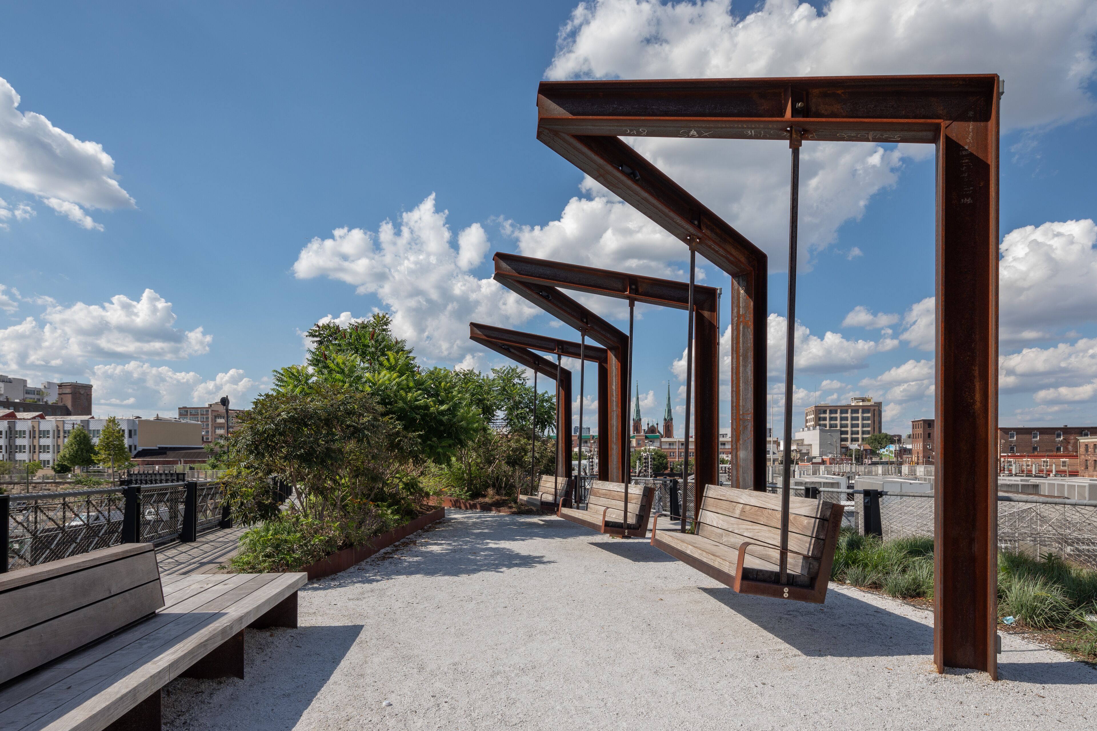 A pedestrian walkway with benches and a metal structure.