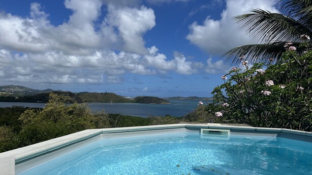 Une piscine d’un bleu éclatant, avec vue sur un lac et des collines lointaines.