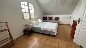 Une chambre à coucher comprenant un lit, une table de chevet, une fenêtre, une commode et une porte.