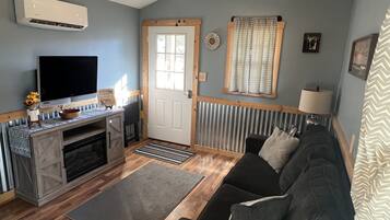 A living room with a TV, sofa, and fireplace.