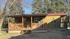 Eine Holzhütte mit Veranda, Terrasse und umzäunter Garten.