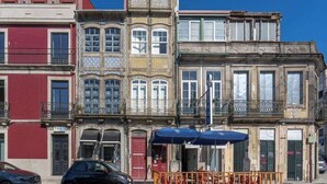 Une rangée de bâtiments colorés dotés de balcons, une voiture garée et un parasol bleu.