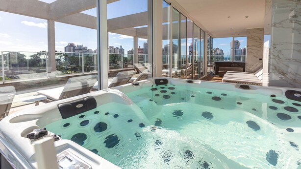 A modern indoor hot tub with a city view, large windows, and a minimalist design. - Hotel Solerios Mansa (Punta del Este)