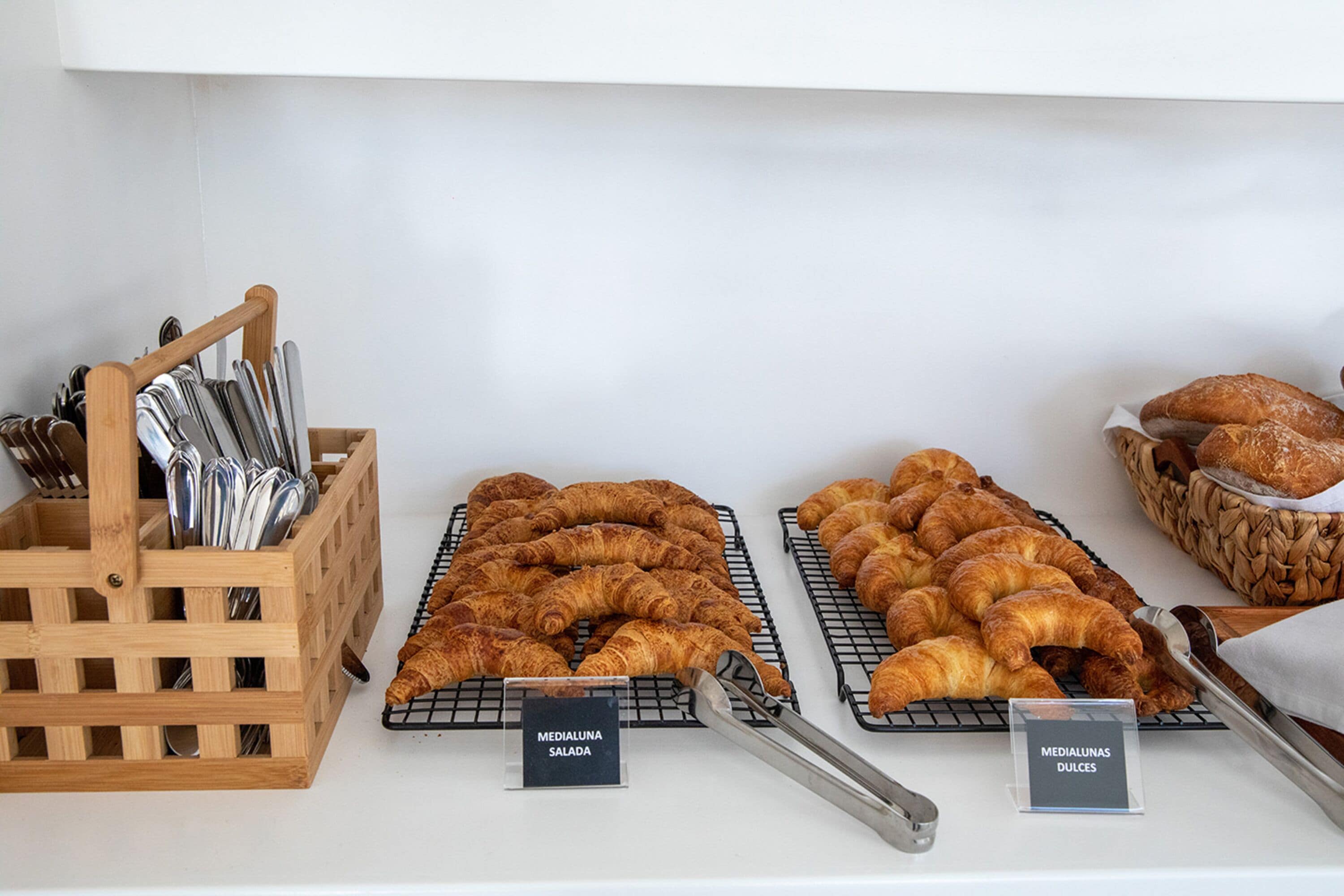 A bakery display with various types of pastries and a wooden utensil holder.