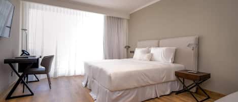 A modern hotel room with a large bed, a desk, and a chair.