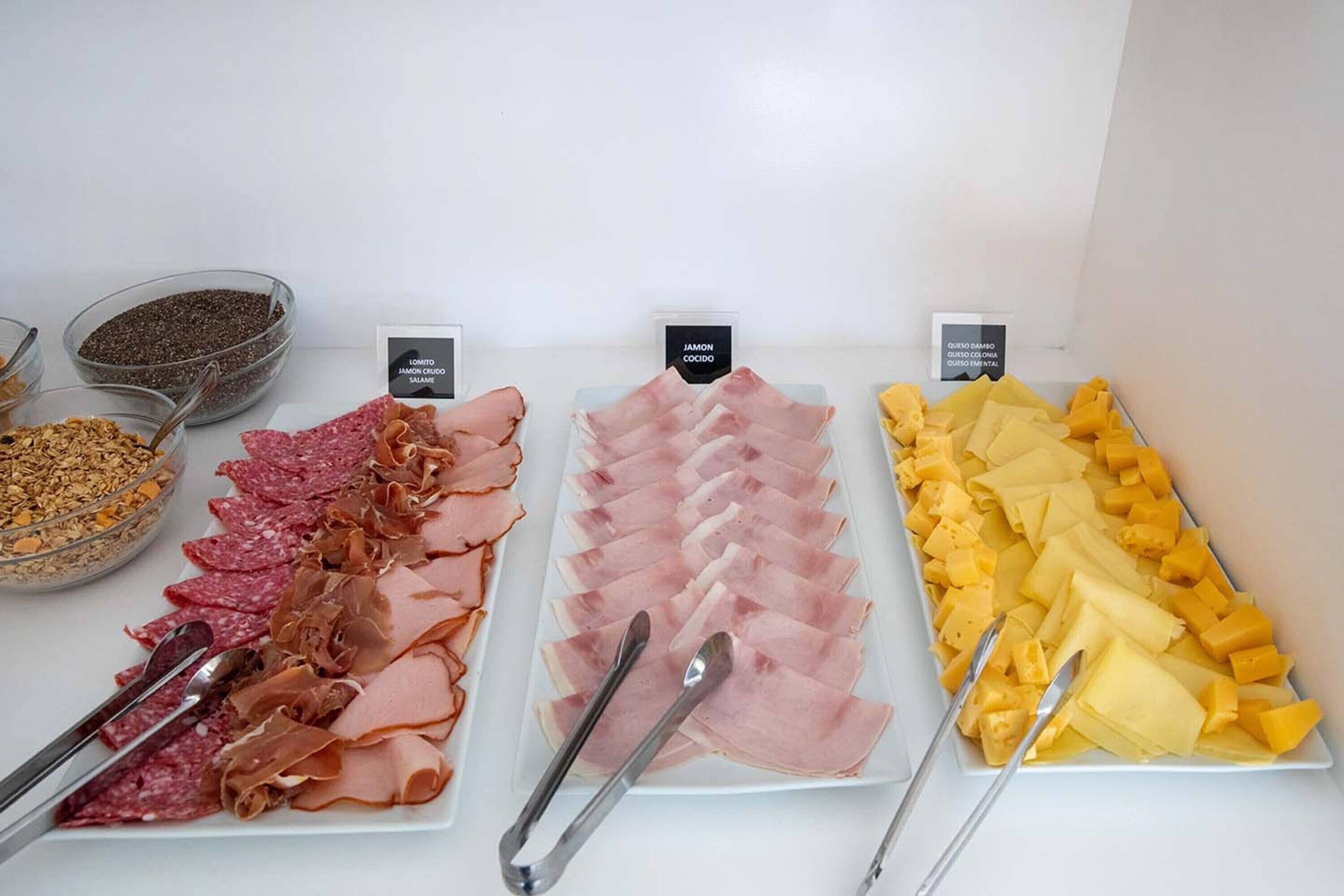 A variety of deli meats and cheeses arranged on plates with labels.