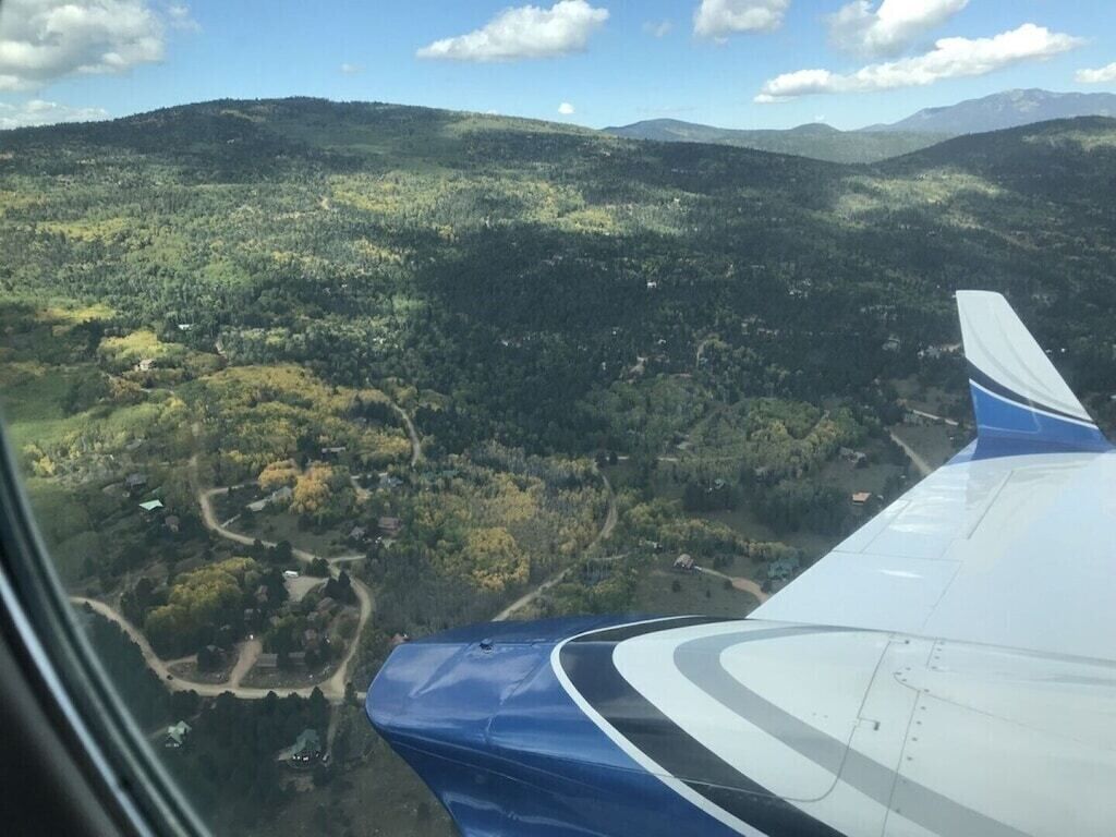 An airplane wing with a view of a mountainous landscape below.