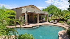 Una casa con piscina, veranda coperta e vegetazione lussureggiante.