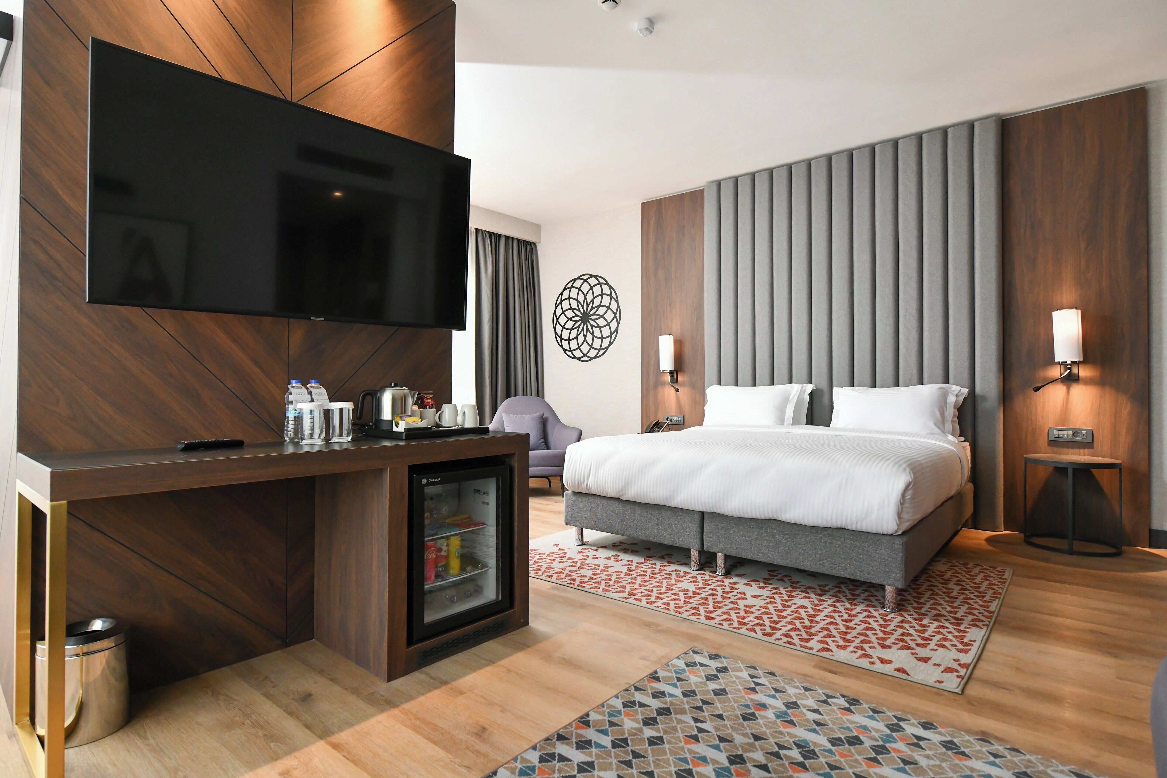 Una habitación de hotel con cama, televisión, minibar y escritorio.