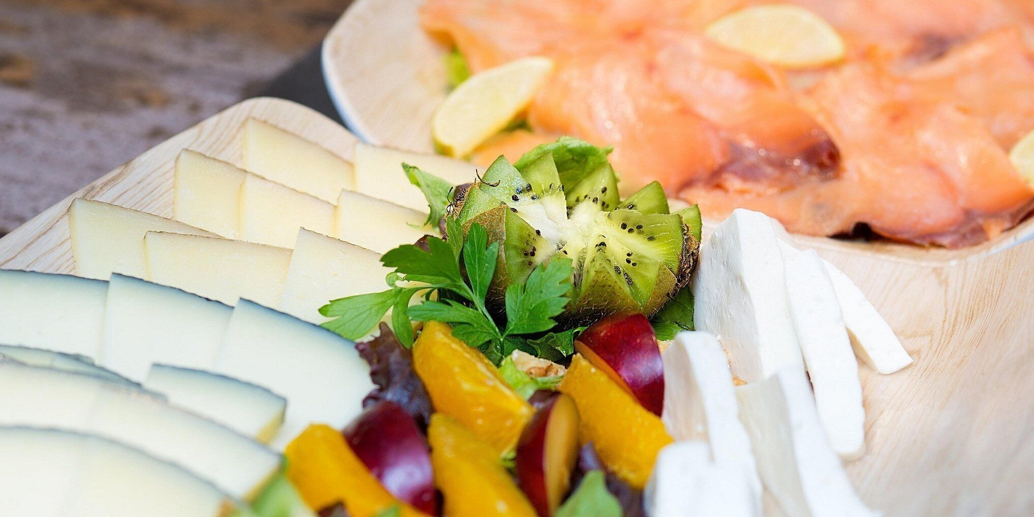 Une planche en bois garnie de différents fromages, de fruits et de saumon fumé.