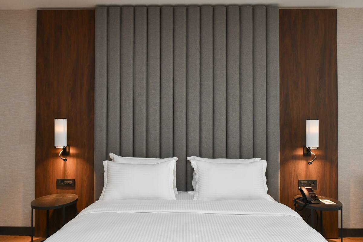 A hotel room with a large bed, two bedside tables, and a modern headboard.