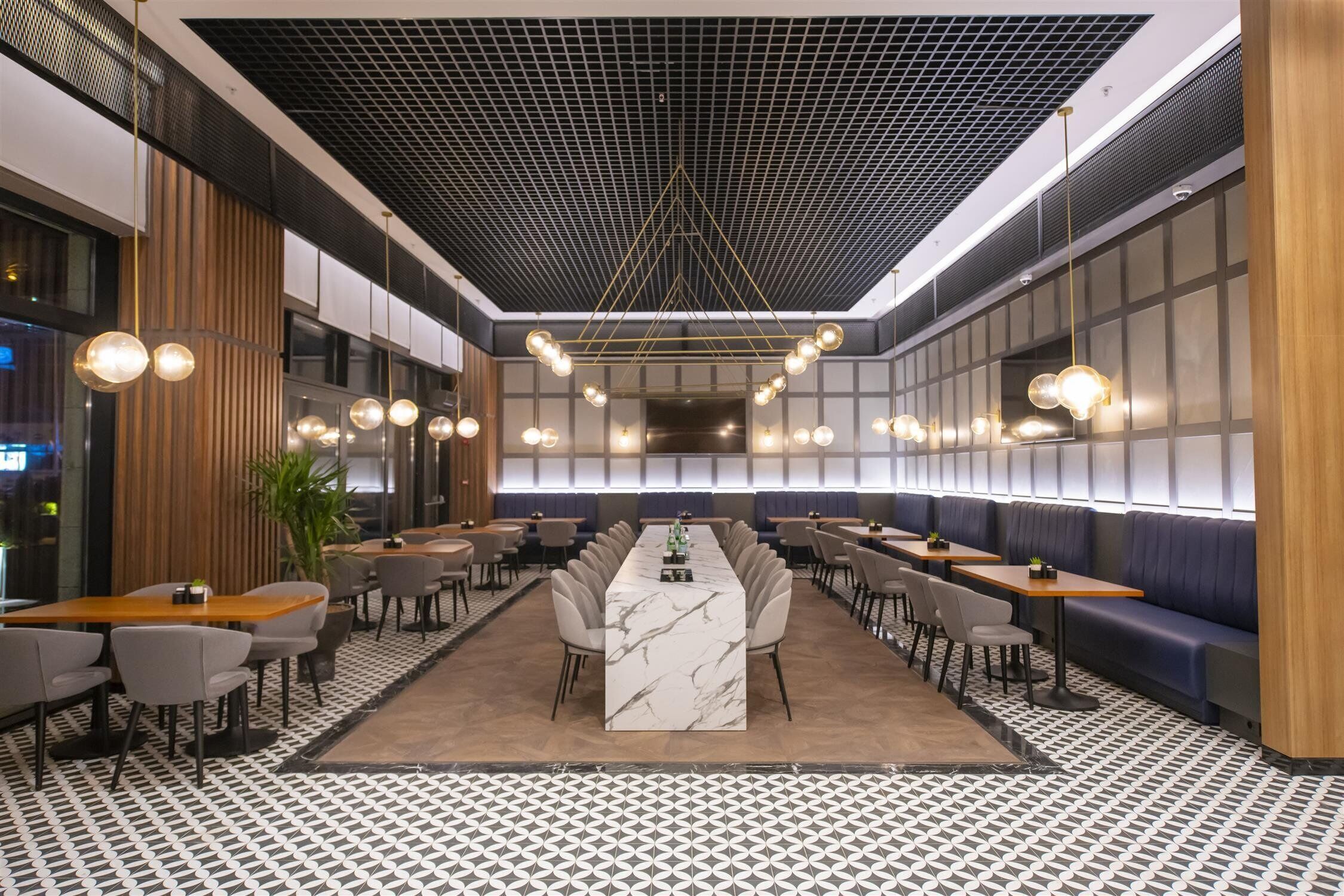 Un restaurante moderno con una larga barra de mármol, varias zonas de estar y un suelo estampado.