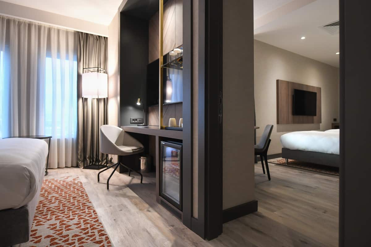 A modern hotel room with a bed, desk, chair, and a television mounted on the wall.