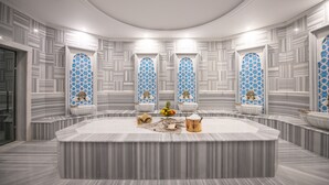 A luxurious bathroom with a large marble sink, decorative tiles, and a central island with toiletries. - Crowne Plaza Ankara by IHG (Ankara)