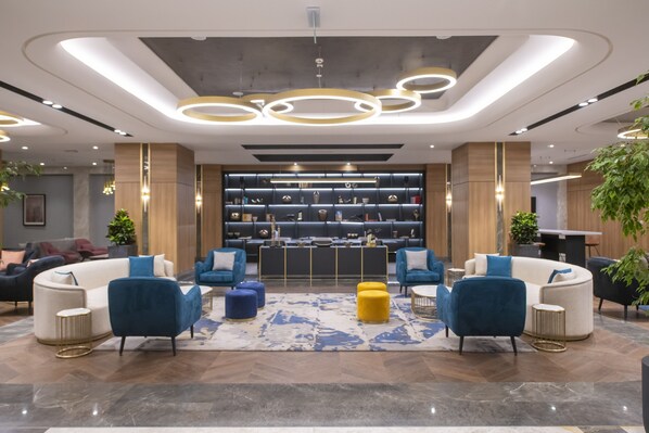 A modern lobby with a central seating area, a display of decorative items, and a reception desk. - Crowne Plaza Ankara by IHG (Ankara)