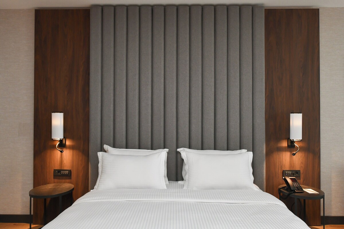 A hotel room with a large bed, two bedside tables, and a modern headboard.