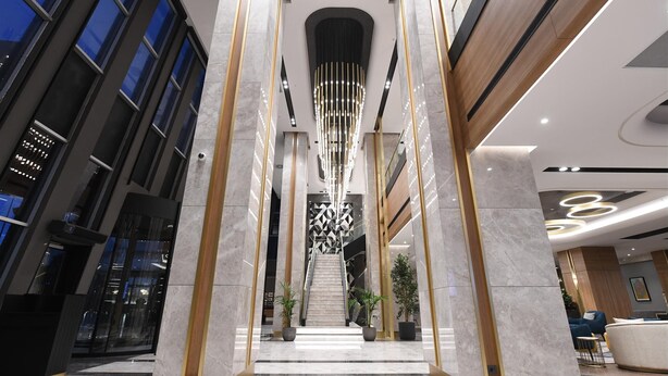 A modern hotel lobby with a central staircase, marble columns, and contemporary lighting fixtures. - Crowne Plaza Ankara by IHG (Ankara)