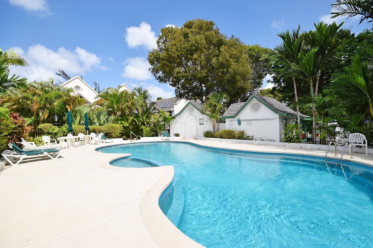 A swimming pool with lounge chairs and a small building.