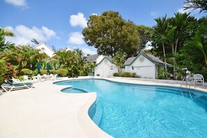 A swimming pool with lounge chairs and a small building.