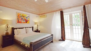 Een slaapkamer met een bed, twee bedlampen, een plafondventilator, een schilderij en een raam met gordijnen.