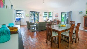 Un amplio salón con una mesa de comedor y sillas, un sofá y una televisión.