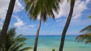 Una playa con agua turquesa cristalina, palmeras y cielo despejado.