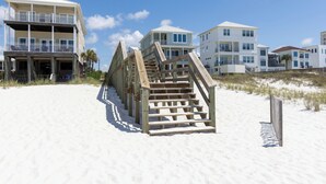 A beachfront property with a wooden staircase leading to a building, a sandy beach, and a clear sky. - "Sunshine At The Beach - Fall Specials! Many Upgrades! Perfect Location! (Orange Beach)